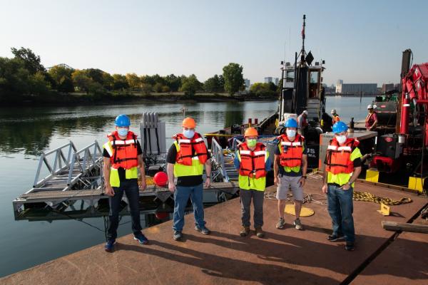 Left to right: Stephen Murray, Jason Valenzano, David Kindler, Paul Ryu, and Andrew March deploy their 8 m × 8 m sonar array test bed, held together by a metal frame, in Boston Harbor for sea tests. 